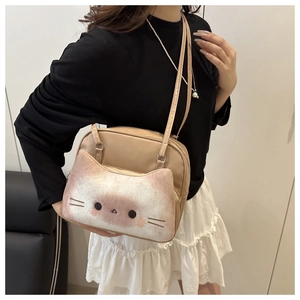 Detail of cute cat-shaped plush pocket on a beige crossbody bag with adjustable strap