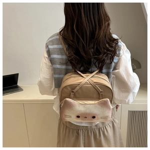 Detail view of beige cat backpack with plush pocket and embroidery on a model