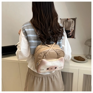 Close-up of cute cat-shaped plush pocket on a beige functional women's backpack