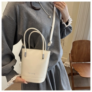 Close-up of beige minimalist bucket bag with silver lettering and smooth leather texture