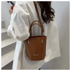 Detail of caramel leather bucket bag with silver Fashion lettering and shoulder strap