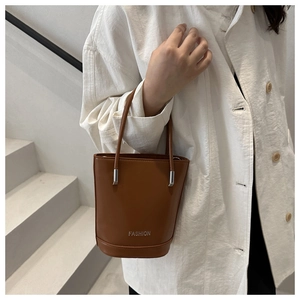 Detail of a brown leather bucket bag featuring a silver metal buckle and FASHION logo