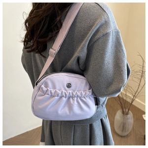 Detail of lavender fabric crossbody bag with adjustable strap and pleated front pocket