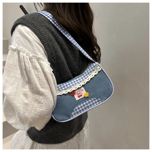 Detail of denim shoulder bag with cherry embroidery, lace trim and blue checkered edge