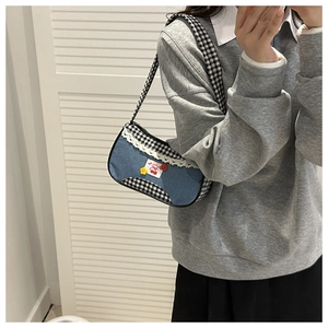 Detail of blue denim and plaid shoulder bag featuring lace trim and cherry embroidery