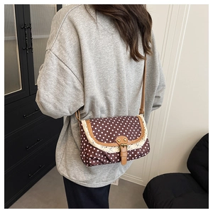 Detail of vintage polka dot crossbody bag featuring white lace trim and leather strap