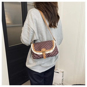 Close-up of retro polka dot canvas bag with white lace trim and leather buckle
