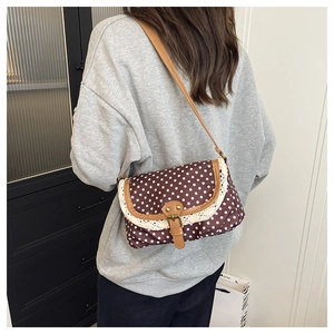 Close-up of vintage brown polka dot canvas bag with white lace trim and leather strap
