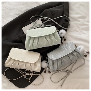 Detailed view of gathered cloud crossbody bags in light green, beige, and grey with chains