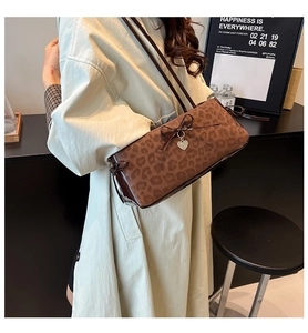 Detail of leopard print shoulder bag with bow and heart charm on a trench coat model