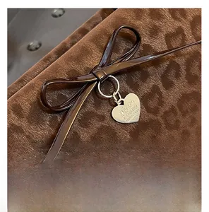 Macro shot of a leopard print bag detail with a dark brown bow and engraved silver heart tag