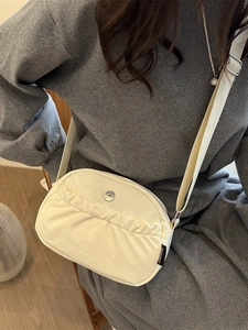 Chic beige half-moon crossbody bag with adjustable strap and stylish metal logo detail