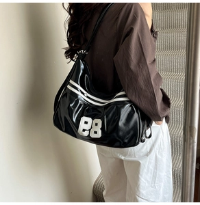 Detail of black glossy shoulder bag featuring white number 28 patch and retro sporty stripes