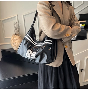 Detail of glossy patent leather tote bag with white stripes and 89 embroidery detail
