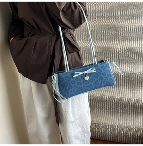 Detail of blue leopard print faux suede shoulder bag with ribbon bow and heart charm