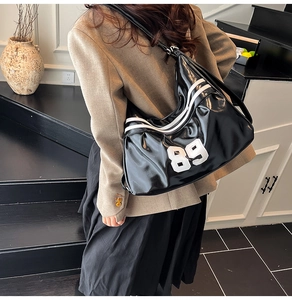 Detail view of black glossy shoulder bag with retro sports number 89 and white stripes
