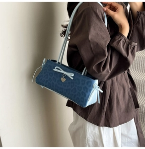 Detail view of the blue leopard print shoulder bag featuring a stylish bow and heart pendant
