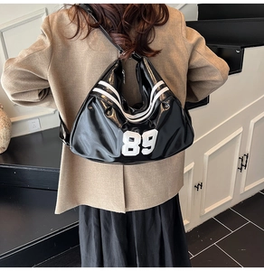 Detail of glossy black crescent bag with white number 89 print and sporty stripes