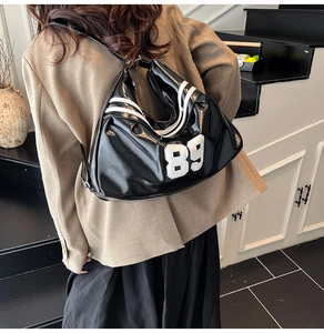 Close-up of glossy black patent leather bag with white 89 numeric patch and sporty stripes