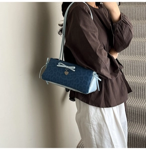 Detail of blue leopard print shoulder bag with bow and heart charm on a model