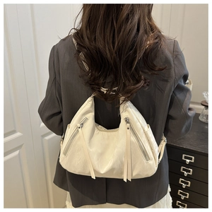 Rear view of model wearing white vintage leather tote bag with tassels and zippers