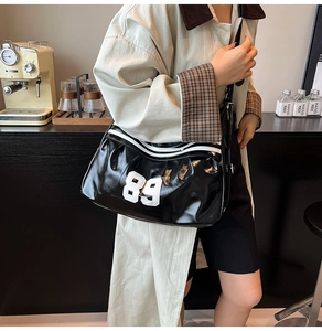 Close-up of black glossy leather bag featuring white number 89 embroidery detail