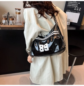 Close-up of black glossy shoulder bag with white number 89 and retro athletic design