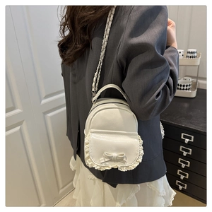 Détail du mini sac à dos blanc avec nœud et dentelle porté en bandoulière