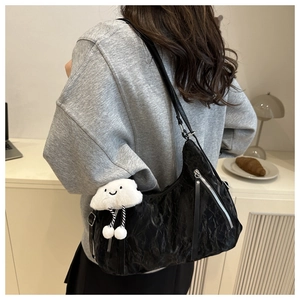 Detail of black pleated hobo bag with silver zipper and white cloud plush pendant charm