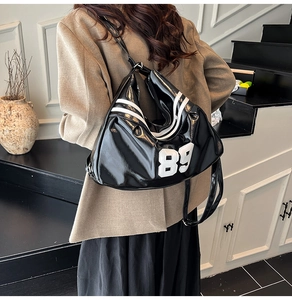 Detail of black glossy leather hobo bag featuring white side stripes and number 89 print