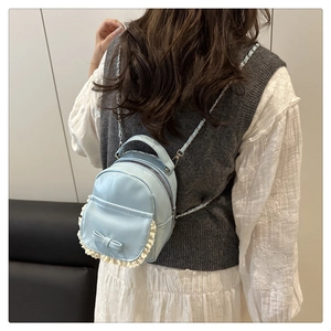 Vue de dos d'un mini sac à dos bleu clair avec un nœud et des bordures en dentelle