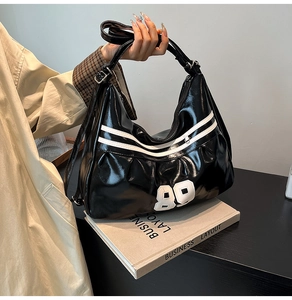 Close-up of shiny black patent leather bag with white 89 patch and sports webbing