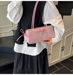 Detailed view of pink satin shoulder bag with bow knot and silver heart charm accessory