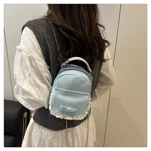 Détail d'un mini sac à dos bleu clair en cuir avec nœud et bordure en dentelle blanche
