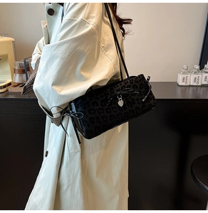 Detail of black leopard print shoulder bag with bow tie and silver heart charm decoration