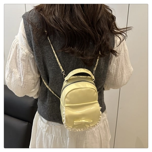 Detail of cream mini backpack with lace trim and bow accent shown on model back