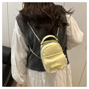 Détail d'un mini sac à dos jaune avec bordure en dentelle blanche et noeud décoratif
