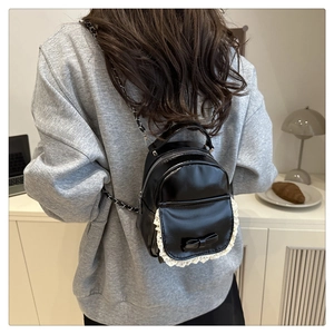 Vue arrière d'un mini sac à dos en similicuir noir avec dentelle et nœud porté par un mannequin