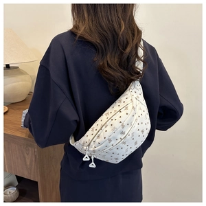 Detail van de witte crossbodytas met bloemen- en strikmotief en verstelbare schouderriem