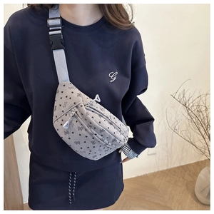 Detailweergave van een grijze corduroy crossbodytas met hartjes en strikjes op model