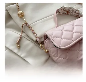 Detail of pink quilted leather bag with gold chain strap, small gold ball and floral scarf