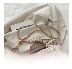 Detail of pink quilted handbag with silk scarf handle and golden chain strap