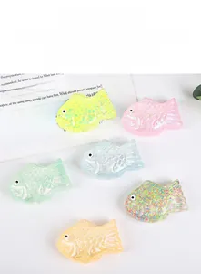 Top view of colorful carp squishy toys with glitter on a white table next to a book