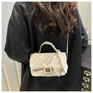 Detail of beige quilted flap bag with gold chain strap and silk scarf handle accent