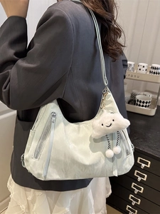 Light green crescent shoulder bag with vertical zippers and plush cloud charm accessory