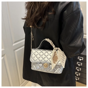 Close-up of a silver quilted chain bag with a decorative geometric silk scarf handle