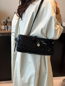 Leopard print bow shoulder bag in black faux fur with glossy patent leather accents