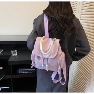 Detailansicht eines lila Nylon-Rucksacks mit Seilgriffen und blauer Bestickung