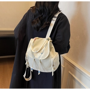 Detail eines weißen Canvas-Rucksacks mit Smile-Stickerei und dekorativem Perlenzugband