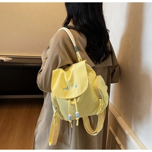 Detailansicht gelber Mini-Rucksack aus Nylon mit blauer Stickerei und Perlenzugband